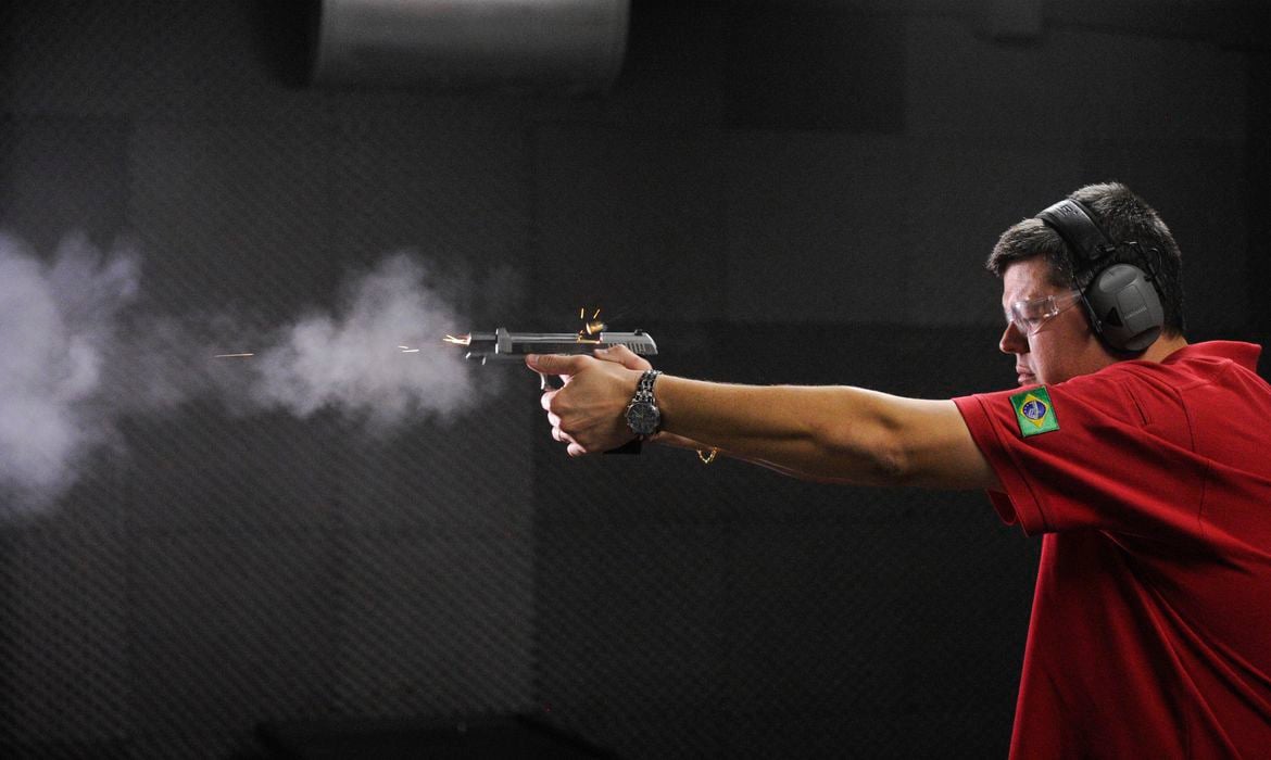 homem com arma em clube de tiro