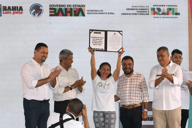 Mulher agricultora levanta placa que recebeu em homenagem ao Dia Internacional da Agricultura familiar ao lado do governador da Bahia, Jerônimo Rodrigues e representantes do estado